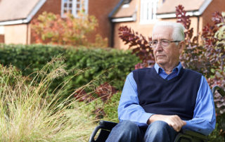 Depressed Senior Man Sitting Outdoors In Wheelchair