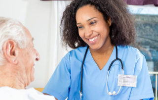 Caregiving nurse happy with elder patient in hospital bed.