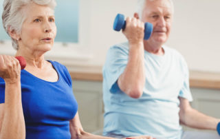 Senior couple sitting on fitness balls with dumbbells